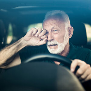 Image of person rubbing their eye while driving