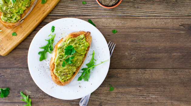 Avocado toast on a plate sitting on a table.