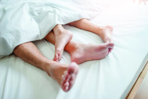 Image of a couple's feet sticking out from under the bedsheets