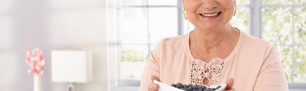 Smiling senior woman holds a bowl of brain supporting blueberries