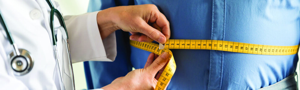 Doctor wrapping a measuring tape around a man's stomach.