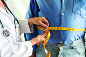 Doctor wrapping a measuring tape around a man's stomach.