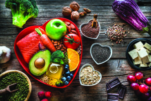 A group of fresh multicolored foods to help lower cholesterol levels and for heart care shot on wooden table. 