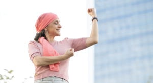 Woman with pink headscarf flexing biceps and smiling