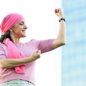 Woman with pink headscarf flexing biceps and smiling