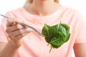 Woman holds fork of memory supporting spinach