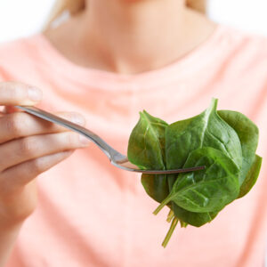 Woman holds fork of memory supporting spinach