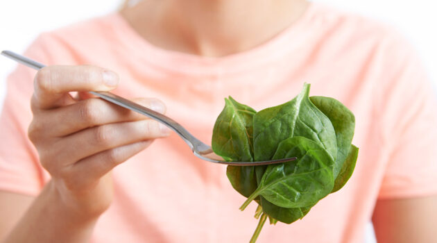 Woman holds fork of memory supporting spinach