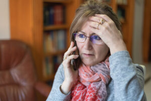 Senior woman on phone feeling stress.