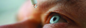 Close up of man dripping eye drops into his eye.