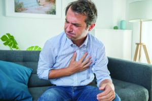Man with hand on chest suffering from symptoms of GERD.