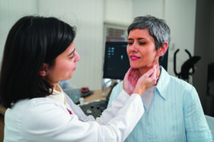 Female doctor palpating female patient's thyroid gland.