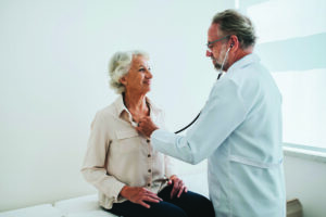 Doctor listening to senior woman patient heartbeat
