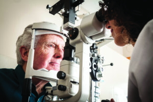 Optometrist giving eye exam to senior patient