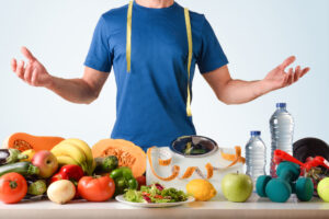 Man standing behind table with healthy foods and exercise equipment