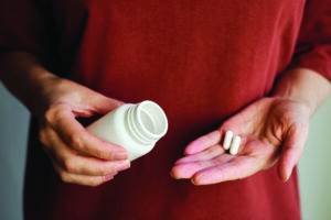 A woman pours magnesium pill supplement from bottle into hand