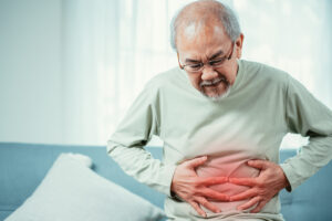Asian Senior man holding stomach in pain.