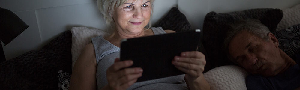 Woman reads tablet in bed increasing diabetes risk.
