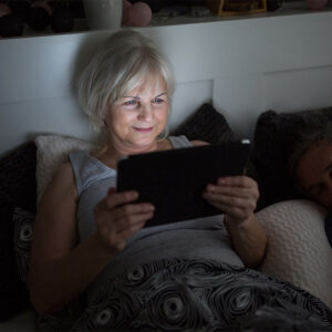 Woman reads tablet in bed increasing diabetes risk.