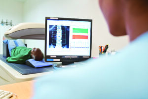 Female nurse analyzing DEXA scan on computer monitor