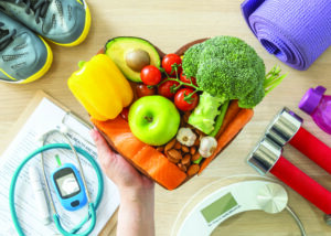 Arrangement of healthy foods in a heart shape alongside exercise equipment.