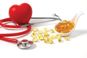 Vitamin pills in front of a stethoscope and heart figure