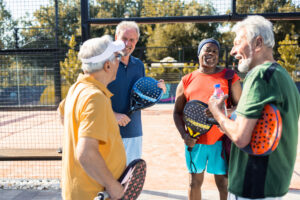 Four senior friends enjoying together while playing paddle tennis