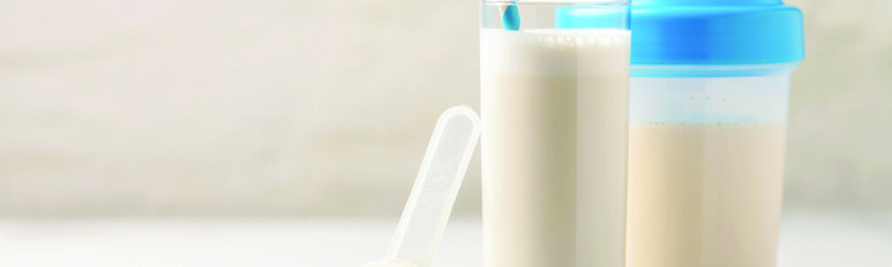 Whey protein powder and mixing bottle with a glass and a straw