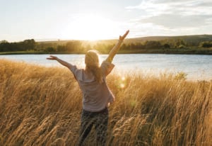 Relaxed woman enjoying fresh air at windy lake during autumn sunset. Freedom and happiness outdoors